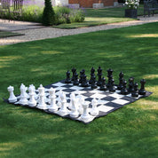 chess pieces on giant chess mat outdoors on grass