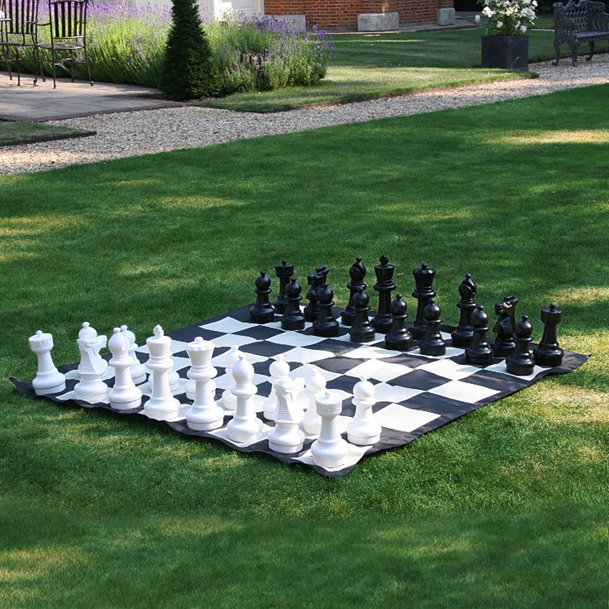 chess pieces on giant chess mat outdoors on grass