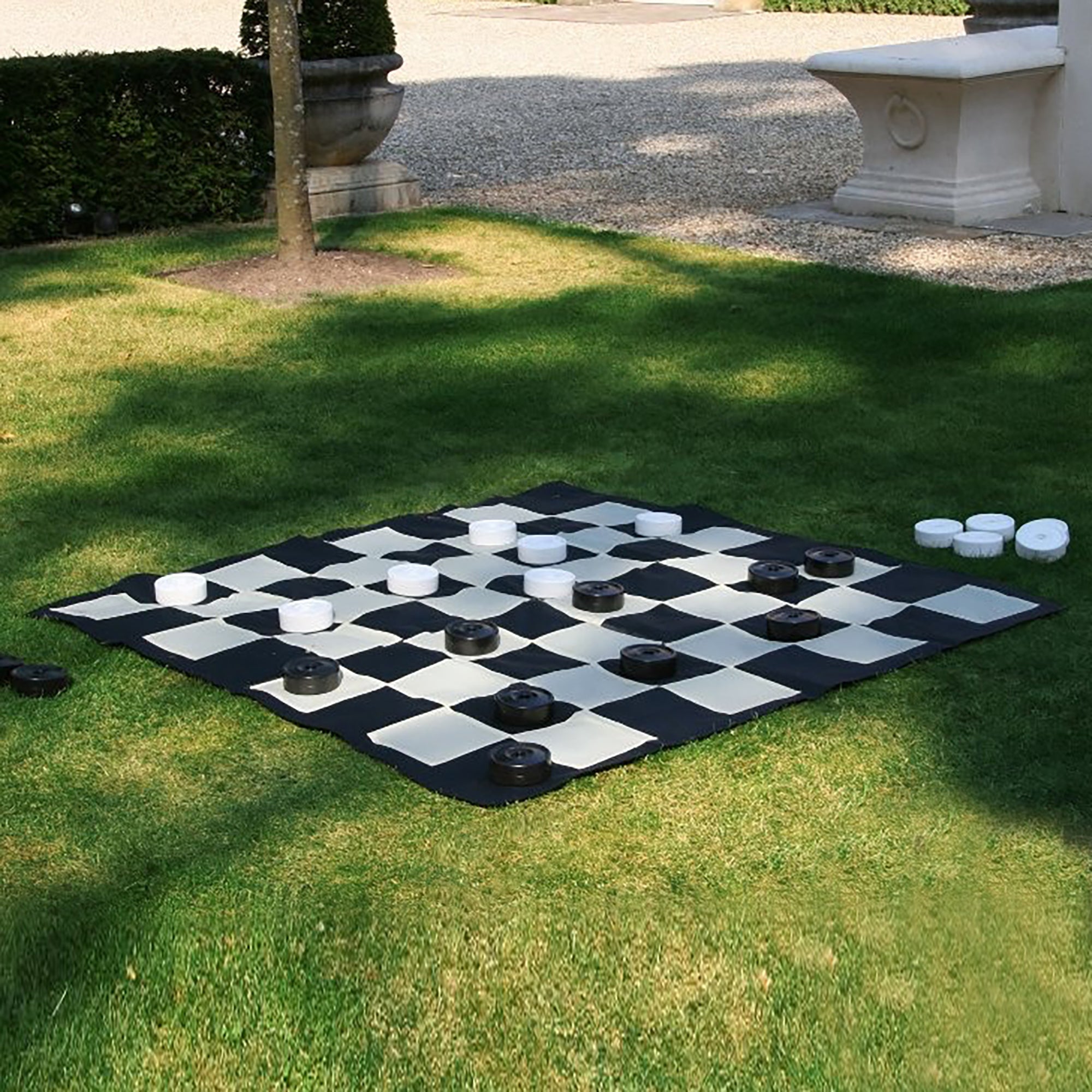 checkers pieces on giant checkers mat outdoors on grass